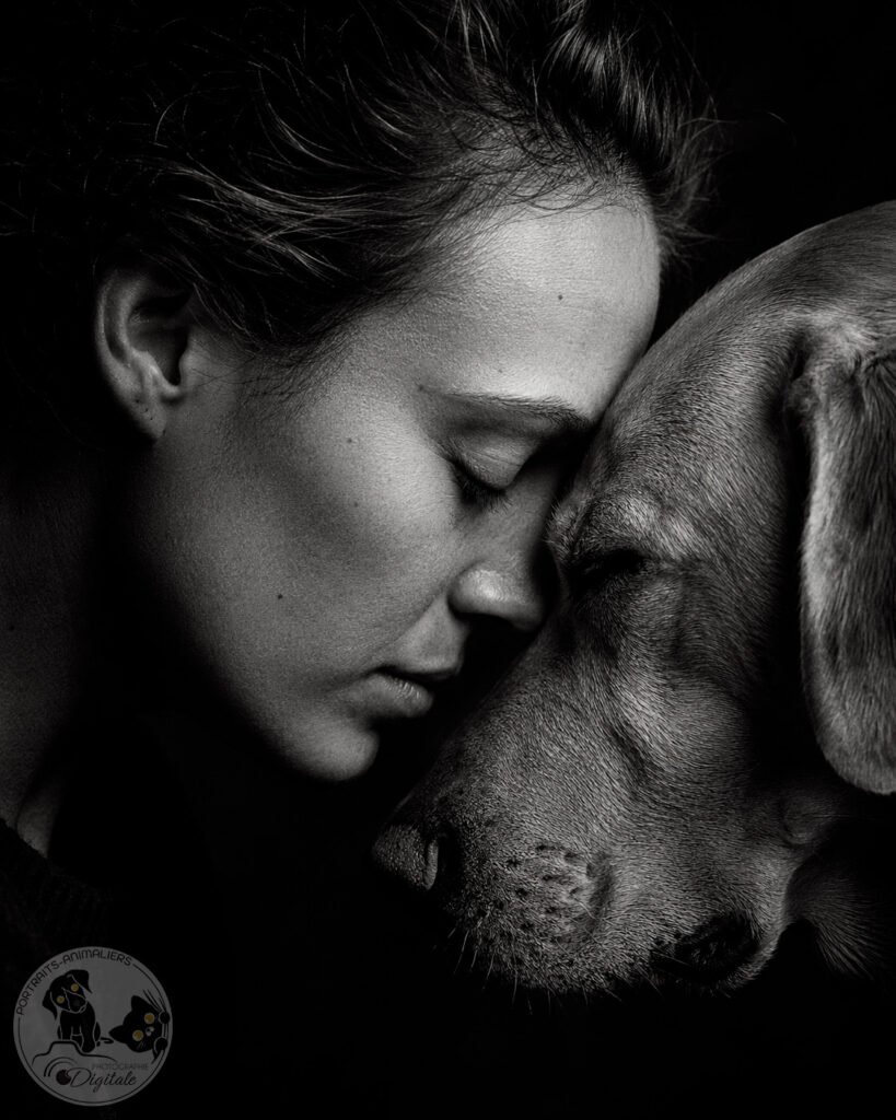Complicité d'une jeune femme et de son chien front contre front noir et blanc